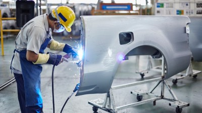 Ein Arbeiter, der an einem Teil eines Fahrzeugs mit einem Schweißgerät arbeitet.