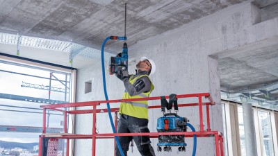 Ein Arbeiter steht auf einer Anhöhe und arbeitet mit einem Trockenbau-Werkzeug und bearbeitet eine Decke.