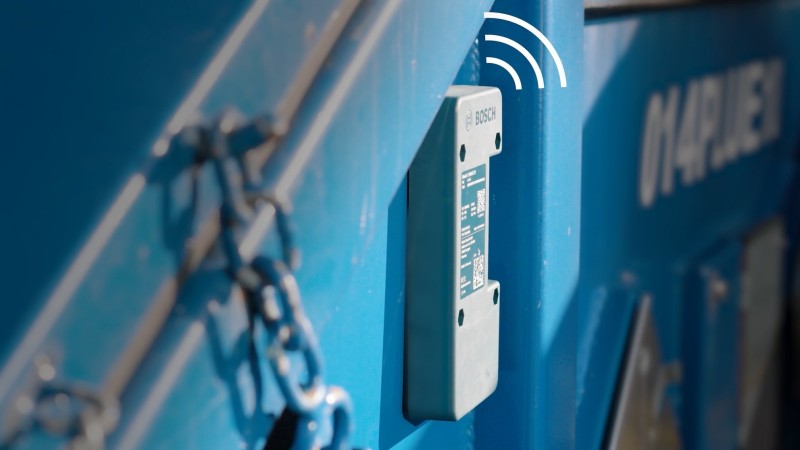 Ein Sensor angebracht an einer Seite eines Containers, über dem Sensor ist ein digitales Signal-Icon.